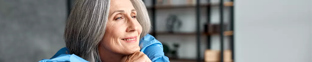 lächelnde-aeltere-frau-mit-blauer-bluse-auf-sofa